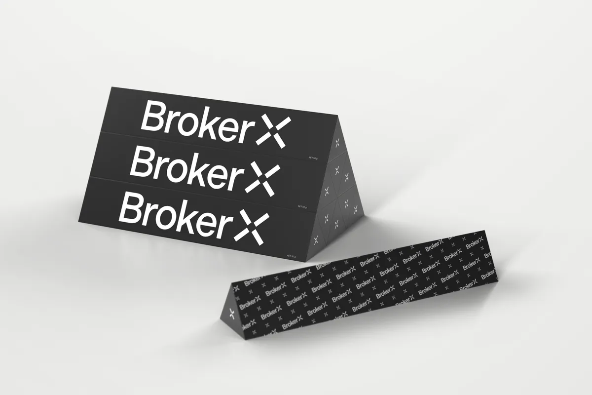 Render of three Broker X branded Toblerone bars stacked into a pyramid, with a fourth bar in front showing the repeating Broker X logo pattern